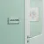 Plaque de porte « LOCAL SONO » posée sur une porte vert d'eau en intérieur