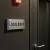 Plaque « LOCAL SONO » installée sur une porte sombre, avec un voyant rouge en hauteur