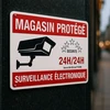 Autocollant « Magasin protégé » surveillance électronique 24h/24h, caméra noire, posé en légère perspective sur fond sombre