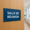 Panneau personnalisé allongé en PVC rigide bleu, vissé sur une porte de bureau en chêne clair