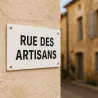 Bandeau personnalisé en PVC rigide blanc, posé en plaque de rue sur un mur enduit