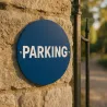 Panneau personnalisé rond en aluminium Dibond bleu, boulonné sur un mur de pierre près d'un portail