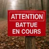 Panneau Attention battue en cours sur un poteau en bord de chemin forestier