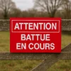 Panneau Attention battue en cours vissé sur une barrière en bois