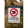 Panneau déjections canines au nom de la commune sur un muret de village